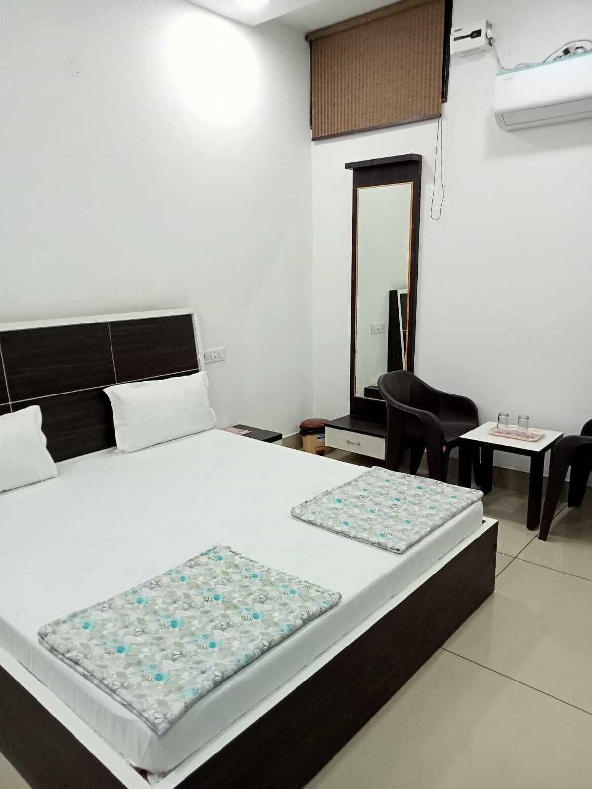 Une chambre d’hôtel avec un grand lit, un bureau, deux chaises, un miroir et un appareil de climatisation.