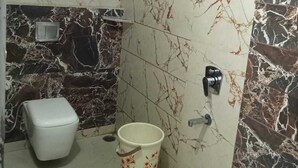 Un baño con inodoro, un cubo y ducha.