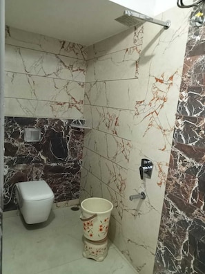 Un baño con inodoro, un cubo y ducha.