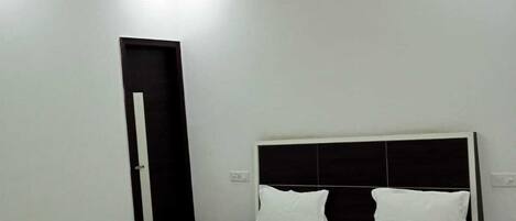 A bedroom with a bed, a ceiling fan, a door, and a nightstand.