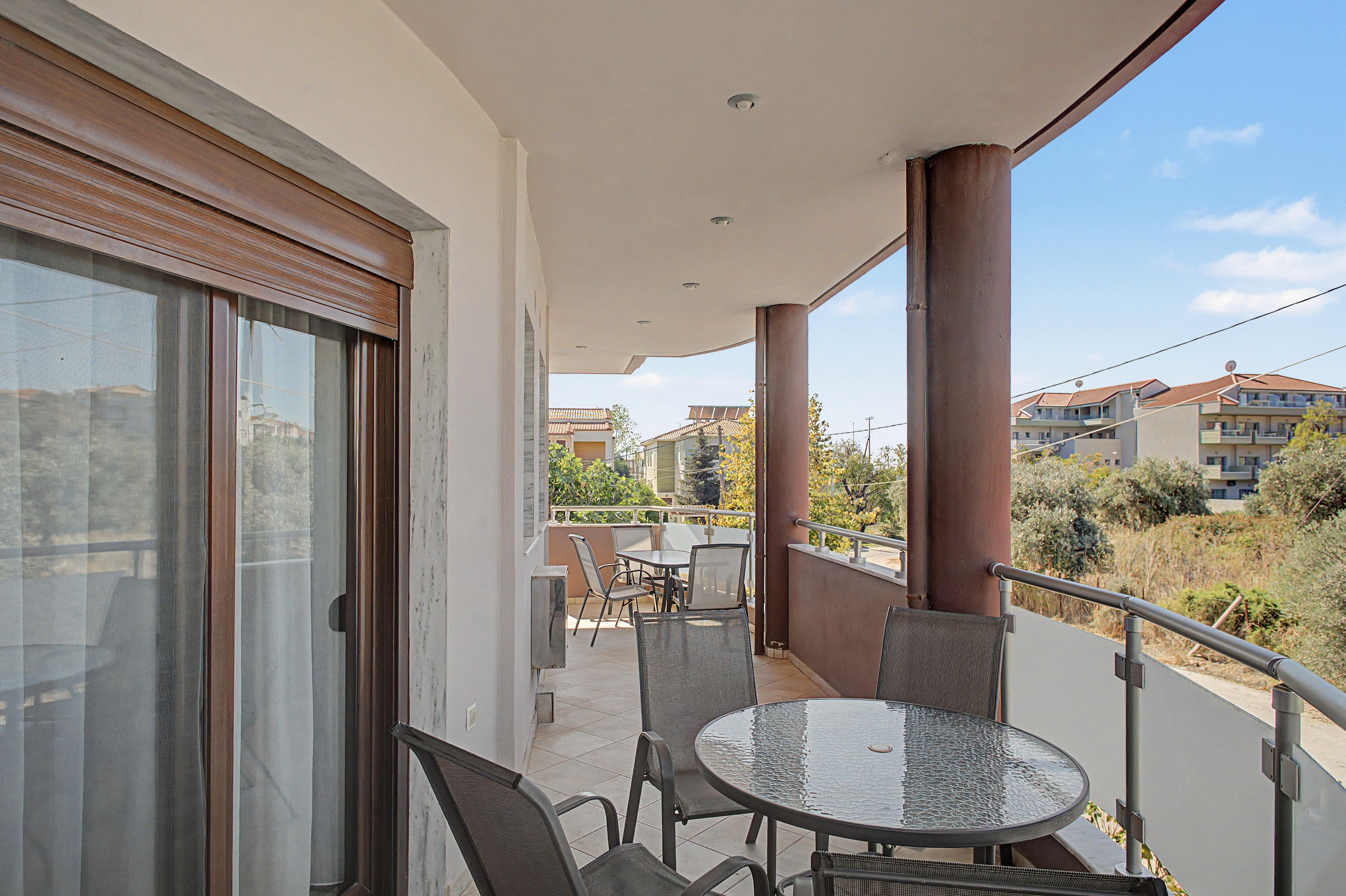 Ein Balkon mit Glastür, einem runden Tisch und zwei Stühlen.