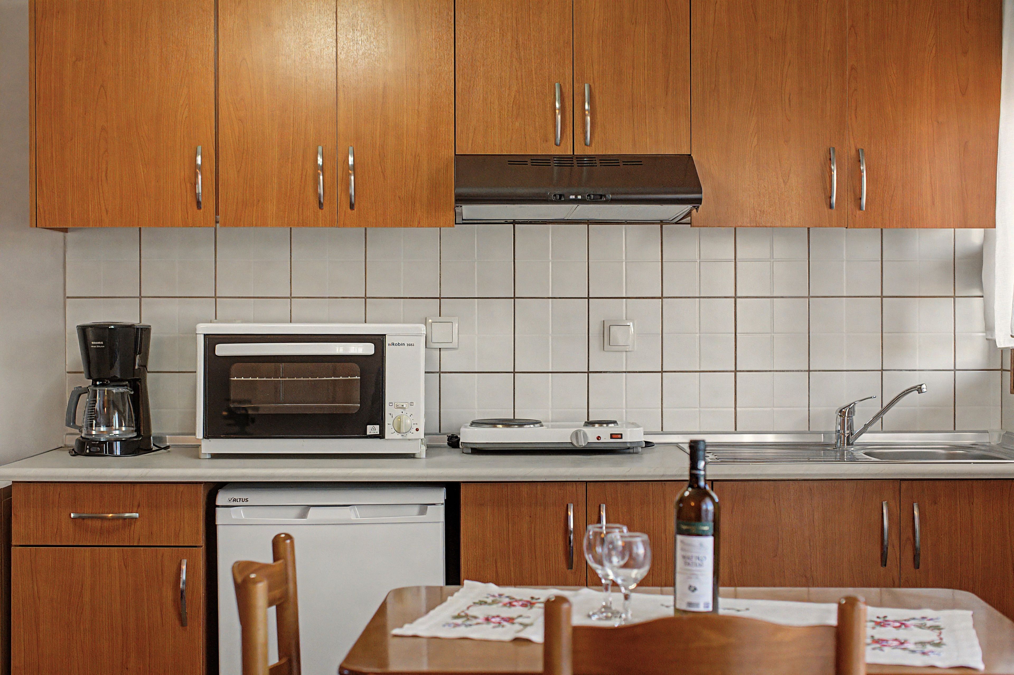 Une cuisine avec des meubles de rangement en bois, un four à micro-ondes, une machine à café, une cuisinière et un évier.