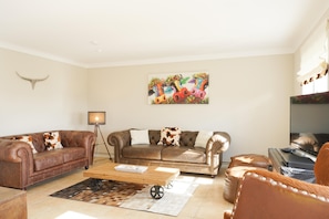A living room with two brown leather sofas, a wooden coffee table, a rug, and a colorful painting on the wall. - Haubarg Ossenhoff apartment for 6 persons near St.Peter-Ording (Tating)