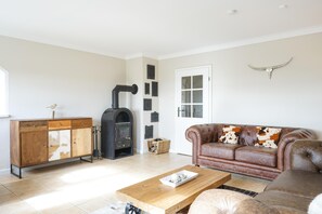 A living room with a fireplace, leather sofa, wooden coffee table, and a cabinet. - Haubarg Ossenhoff apartment for 6 persons near St.Peter-Ording (Tating)