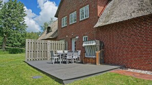 A brick building with a thatched roof, a wooden fence, and a patio with outdoor furniture. - Haubarg Ossenhoff apartment for 6 persons near St.Peter-Ording (Tating)