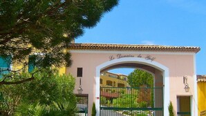 Uma entrada fechada por portão com uma placa indicando 'Le Domaine du Golf' e um céu claro acima.