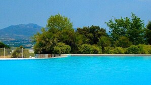 Piscina azul límpida com vista para uma montanha e vegetação exuberante ao fundo.
