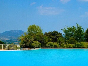 Ein klares, blaues Schwimmbecken mit Blick auf einen Berg und üppiges Grün im Hintergrund.