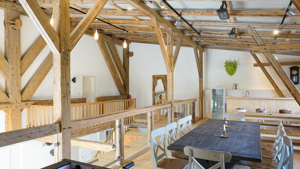 Ein rustikales Interieur mit freiliegenden Holzbalken, einem Tischfußballtisch und einem Essbereich mit Bänken.