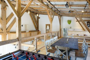 A rustic interior with exposed wooden beams, a foosball table, and a dining area with benches. - Apartment for 2 in the historic Haubarg near St. Peter-Ording (Tating)