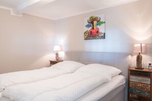 Ein Schlafzimmer mit einem Bett, zwei Nachttischen, einer Wandlampe und einem Gemälde.