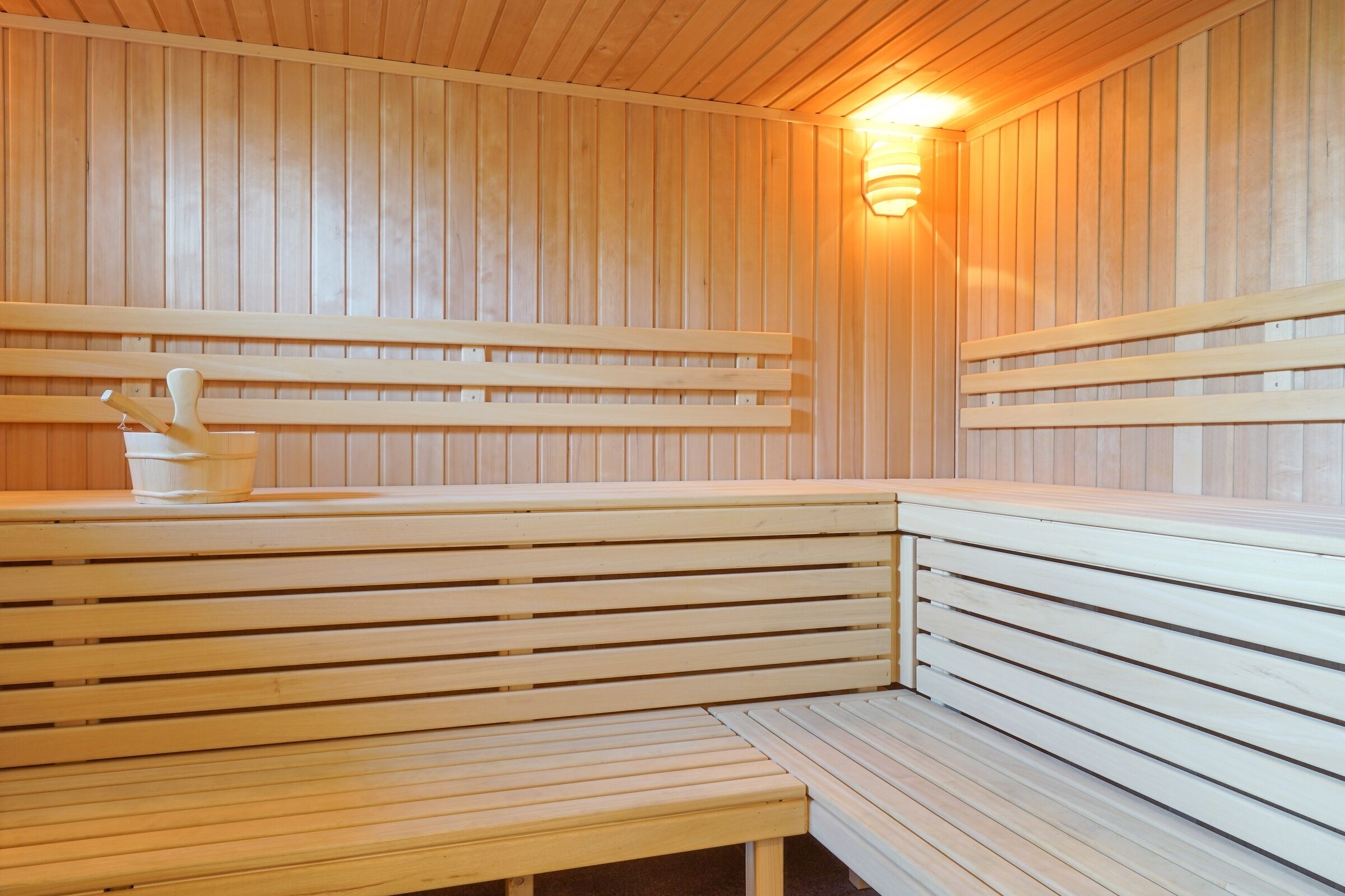 A sauna with wooden benches and a wall-mounted light fixture.