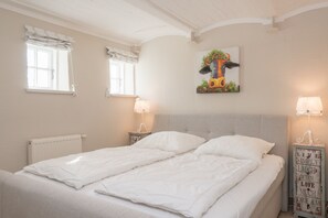 Ein Schlafzimmer mit einem Doppelbett, zwei Nachttischen mit Lampen, einem Heizkörper und einem Wandbild.