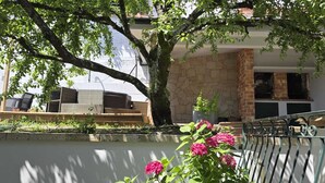A patio area with wicker furniture, a tree, and pink flowers. - XL house for large tribes in the heart of nature, quick access to Parc Gerês (Braga)