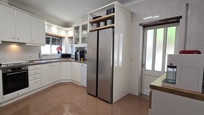 A kitchen with white cabinets, a stainless steel refrigerator, a microwave, and a dishwasher. - XL house for large tribes in the heart of nature, quick access to Parc Gerês (Braga)