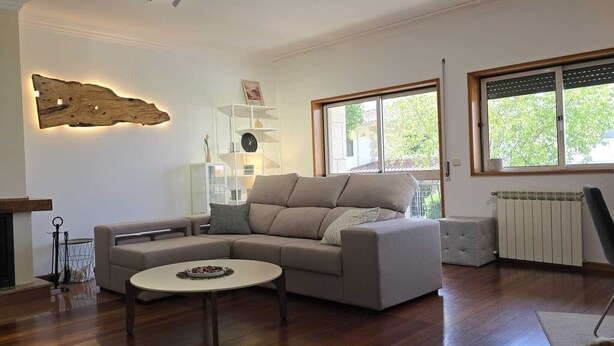 A living room with a sectional sofa, a fireplace, a round coffee table, and a large window. - XL house for large tribes in the heart of nature, quick access to Parc Gerês (Braga)