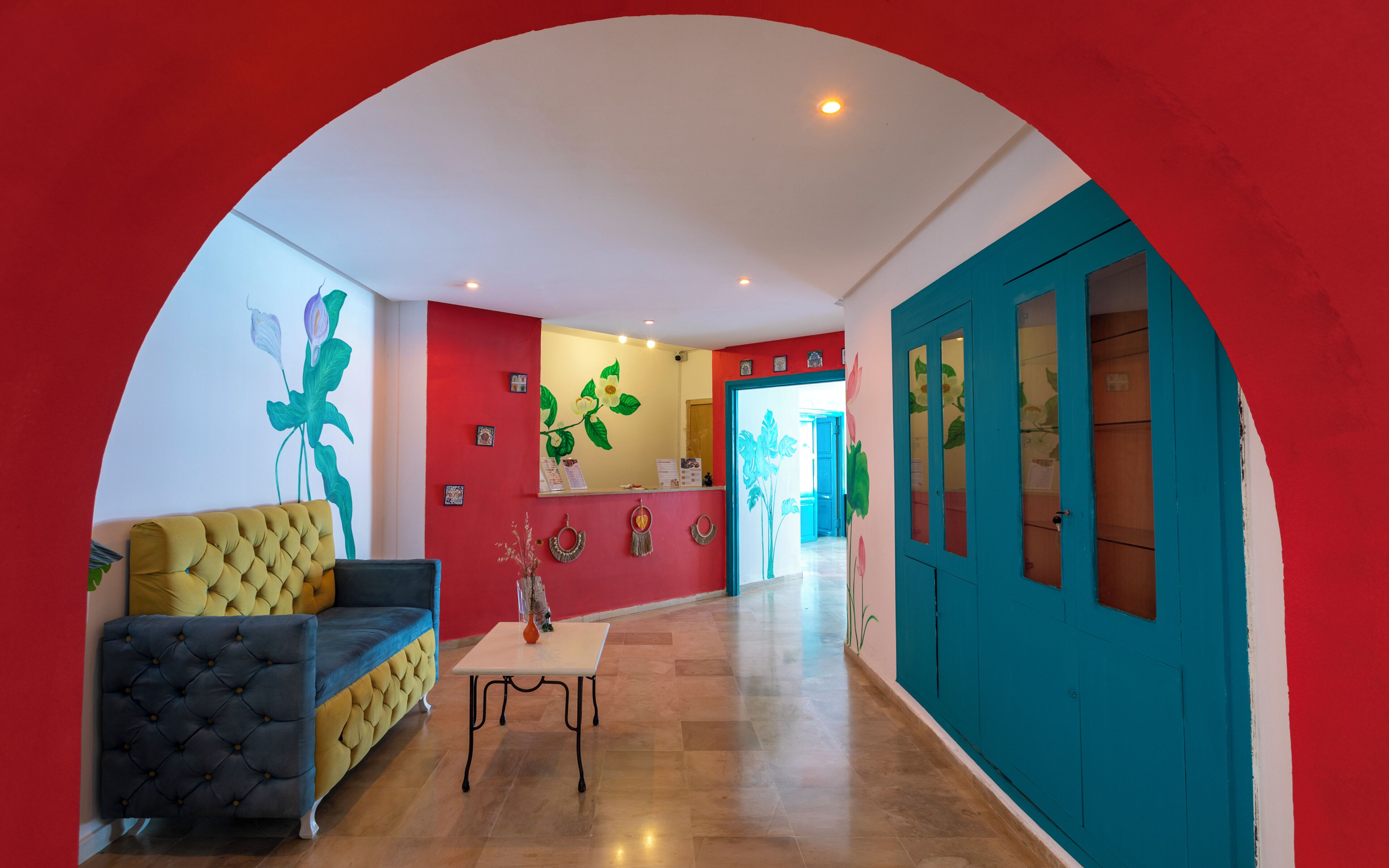 Un hall de hotel con un sofá amarillo, una mesa y una puerta azul.