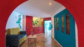 Un hall de hotel con un sofá amarillo, una mesa y una puerta azul.
