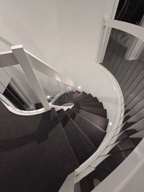 A spiral staircase with glass railings and carpeted steps. - Panoramic View in Narre Warren North (Melbourne)