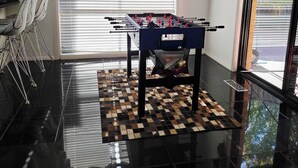 A room with a foosball table, a checkered floor, and a window with blinds. - Panoramic View in Narre Warren North (Melbourne)