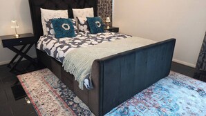 A bed with a dark headboard, a patterned bedspread, and decorative pillows. - Panoramic View in Narre Warren North (Melbourne)