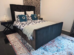 A bed with a dark headboard, a patterned bedspread, and decorative pillows. - Panoramic View in Narre Warren North (Melbourne)