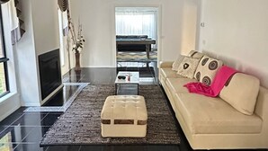 A modern living room with a sofa, ottoman, and a TV. - Panoramic View in Narre Warren North (Melbourne)