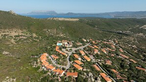 Una vista aerea di un villaggio costiero con case a terrazze, una piscina e un ponte.