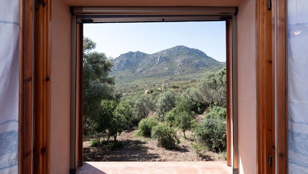 Una stanza con vista su un paesaggio montuoso attraverso un'apertura.