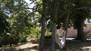 A tree-lined outdoor area with a hammock and stone wall. - Gîte "La Picolina" near Lac des Fades (Charensat)