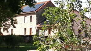A stone building with a sloped roof, a visible window, and a solar panel. - Gîte "La Picolina" near Lac des Fades (Charensat)