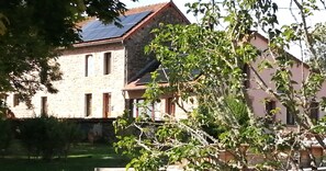 A stone building with a sloped roof, a visible window, and a solar panel.