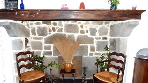 A stone fireplace with two wooden chairs, a vase, and a small table. - Gîte "La Picolina" near Lac des Fades (Charensat)