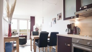 Una cocina moderna con comedor, máquina de café y vistas al exterior.