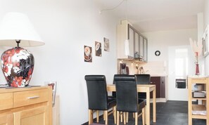A dining area with a table and chairs, a lamp, and a cabinet. - Deichblick Vacation Rental (Schönberg (Holstein))