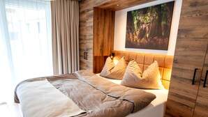 A bedroom with a bed, wooden paneling, a headboard, a wall-mounted light, and a framed picture. - Rauris Penthouse With Fireplace (Rauris)
