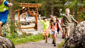 A group of children running on a gravel path in a wooded area with a wooden sign that reads 'OLDWASCHPLATZ'. - Rauris Penthouse With Fireplace (Rauris)