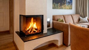 A modern fireplace with a glass front, a wooden floor, a beige sofa, and a painting on the wall. - Rauris Penthouse With Fireplace (Rauris)