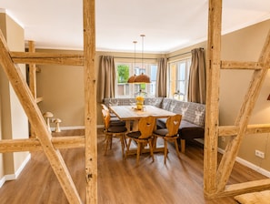 Een eetruimte met een houten tafel, stoelen, een bank en een hanglamp.