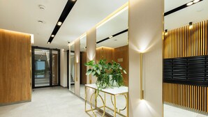 Un hall d’hôtel moderne avec un comptoir d’accueil, une plante en pot et un miroir.