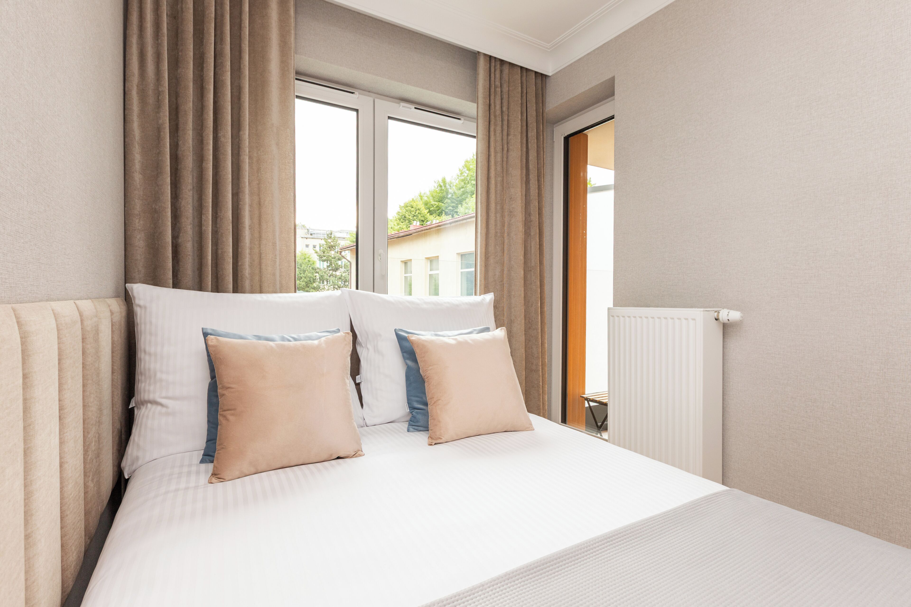 Une chambre d’hôtel avec un lit, des rideaux, une fenêtre et un radiateur.