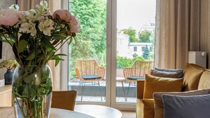 Un salon moderne avec une table à manger, un canapé, un vase de fleurs et une vue à travers une porte vitrée.
