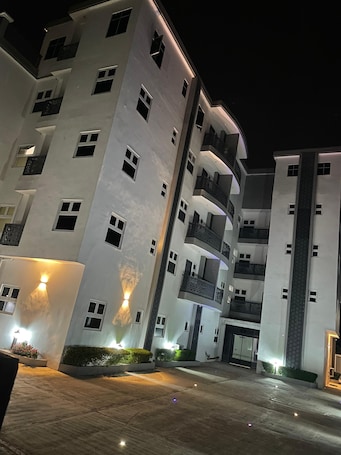 A multi-story hotel with balconies, a central entrance, and illuminated exterior lighting.. Big Apple Hotels