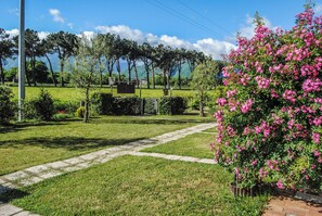 A grassy area with a pathway, trees, and a bush with pink flowers. - Case a Stratola (Montella)