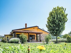 A house with a yellow facade, a stone chimney, and a patio with outdoor furniture. - Case a Stratola (Montella)