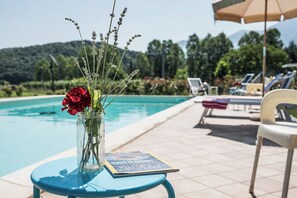 A poolside table with a vase of flowers and a magazine, surrounded by lounge chairs and a pool. - Case a Stratola (Montella)