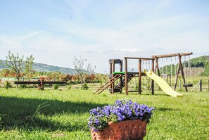 A playground with a slide and climbing structures, surrounded by a grassy field and trees. - Case a Stratola (Montella)