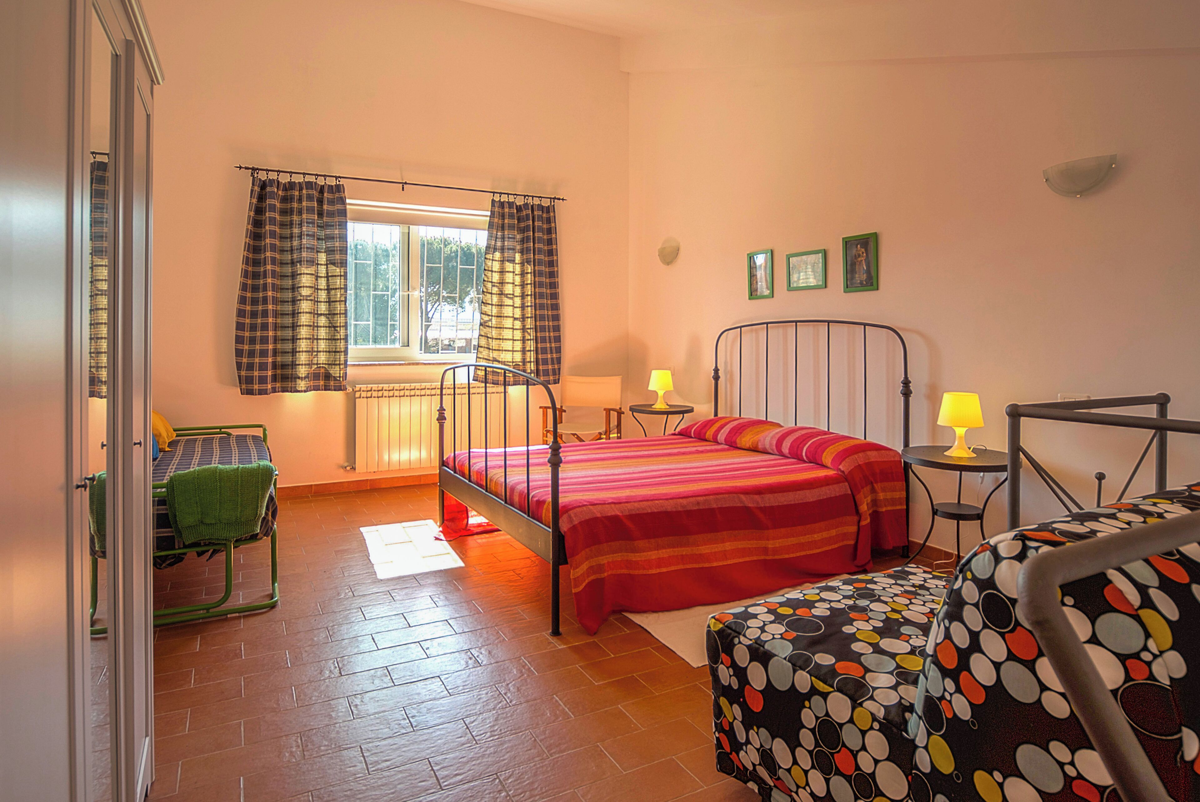 A bedroom with a bed, a chair, a table, and a window with curtains.