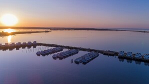 Een ligging aan het water met meerdere huizenboten afgemeerd in rustig water, spiegelend de zonsondergang.