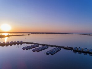 Ein Ufergrundstück mit mehreren Hausbooten, die in ruhigem Wasser vor Anker liegen und den Sonnenuntergang spiegeln.